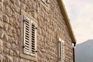 House wall with rustic stone texture and shutters