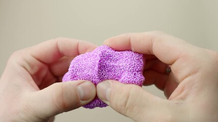 Close-up of fingers squishing purple foam slime in first person view, slow motion