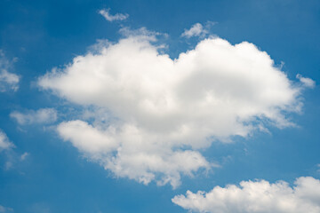 Fluffy white cloud shaped like a heart against a bright blue sky.