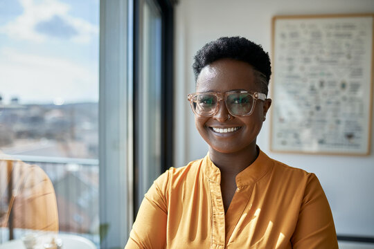 Smiling businesswoman with short hair standing by window at office