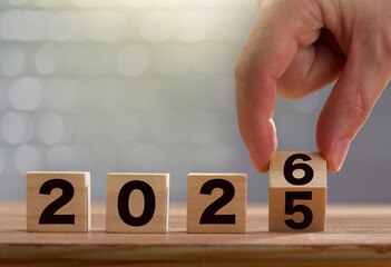 New year change concept. Fingers turning the calendar board block from 2025 to 2026. Graphic poster...