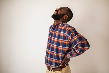 Portrait of exhausted and overworked black man who is having pain in his back.