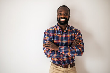 Happy black man in cozy shirt lying on wall with arms crossed and smiling.