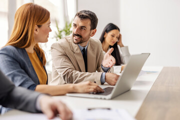Portrait of businessman discussing business plane with colleague at corporate office.