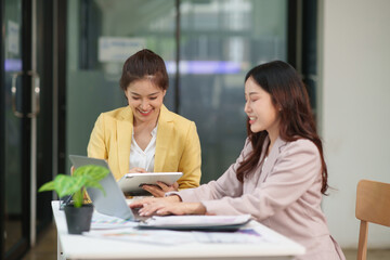 Group of two Asian businesswomen using laptops and tablets having a meeting about working together.