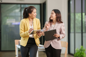 Group of two Asian businesswomen using laptops and tablets having a meeting about working together.