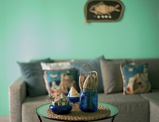 Marine style in the apartment interior - a sofa with pillows and a table with shells and fish figures.