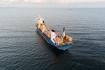 Obraz premium Aerial view of a large blue and red general cargo ship sailing on the calm waters of the Baltic Sea near the coast of Estonia.