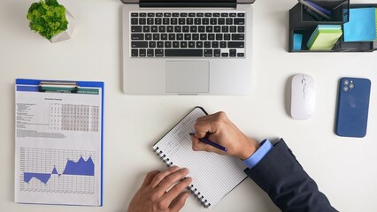 Professional Workspace Setup Featuring Open Laptop and Writing Notepad