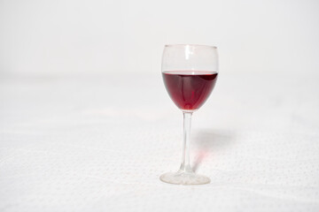 Red wine glass centered on pristine white background. Minimalist composition and even lighting highlight deep, rich red wine color, evoking elegance and refinement