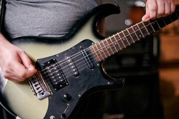 Fototapeta premium Close up of musician hands playing an electric bass guitar, focusing on precise finger placement and frets during practice session performance