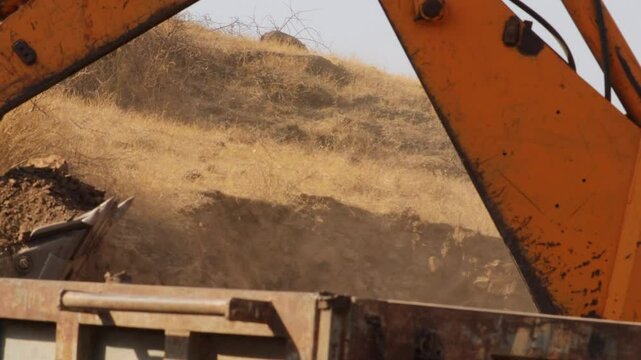 The modern excavator JCB performs excavation work on the construction site. An earth excavator machine at work at india's rural areas. Modern yellow JCB digger or excavator performs excavation