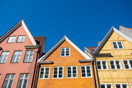 Colorful facades of traditional Copenhagen architecture, blue sky, geometric window frames, Scandinavian design, urban landscape and city charm.