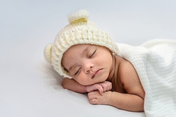 Sleeping Asian baby on a white bed.