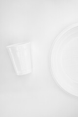 White minimalism with plastic plate and cup on a light background. Simple and balanced composition, ideal for themes of design, consumption, single-use waste, or environmental sustainability.
