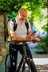 Obraz premium Senior man with bicycle in the city using phone