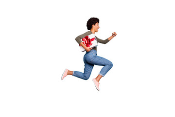Full length profile side photo of funny cheerful brunette wavy hair girl hold big gift hurry to friends anniversary celebration party event jump run wear pullover jeans isolated blue color background