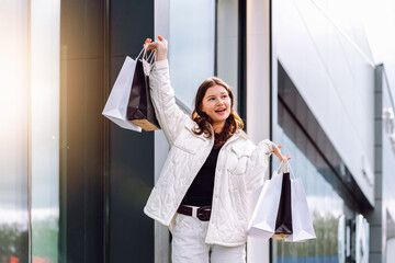 Happy shopper celebrating purchases with bags outside a modern store