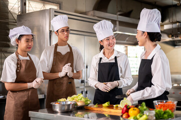 Female chef is laughing while talking with her students or assistant standing around kitchen counter