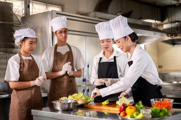 Female chef picking bell peppers while her students or assistants standing around the kitchen counter.
