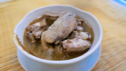 Enjoy eating traditional Chinese delicacies: sesame oil chicken and Soju wine cooked chicken soup — aromatic handmade broth simmered with bone-in chicken thigh pieces and served with dry wheat noodles