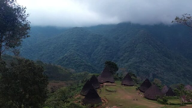 Traditional Mbaru Niang houses of Wae Rebo, Indonesia, nestled amidst lush green mountains. A unique cultural village landscape with Cone-shaped thatched roofs