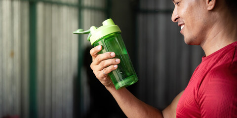 Hydration and Fitness. Man holding a green shaker bottle with water, promoting healthy lifestyle.