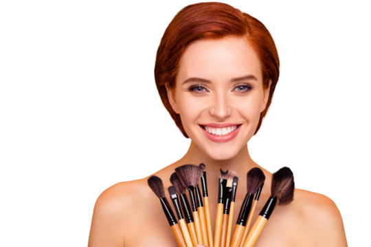 Close-up portrait of nice cute lovely attractive charming cheerful cheery girl smooth clean clear perfect shine skin holding in hands brushes isolated over beige background