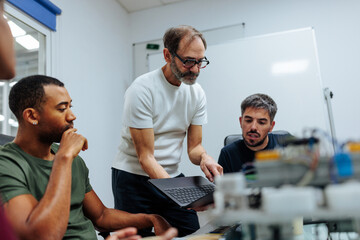 Engineers collaborating on innovative robotics project using laptop