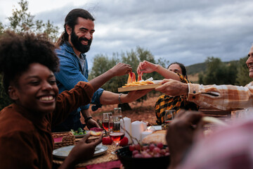 Friends sharing food, laughing and having fun at outdoor dinner party