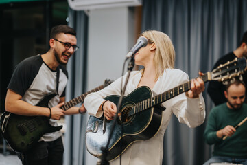 Obraz premium A group of musicians rehearsing in a studio, featuring energetic interaction and focus. The scene includes guitars, a microphone, and drums, forming a cohesive and lively musical ensemble.