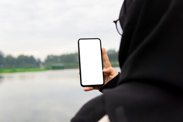 Woman holding mobile phone with blank white desktop screen in the outdoor