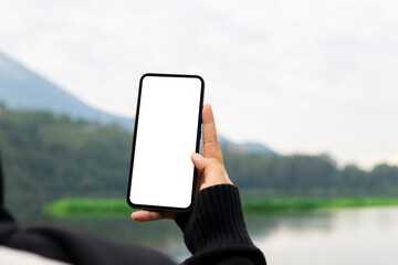 Woman holding mobile phone with blank white desktop screen in the outdoor