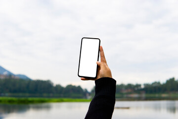 Woman holding mobile phone with blank white desktop screen in the outdoor