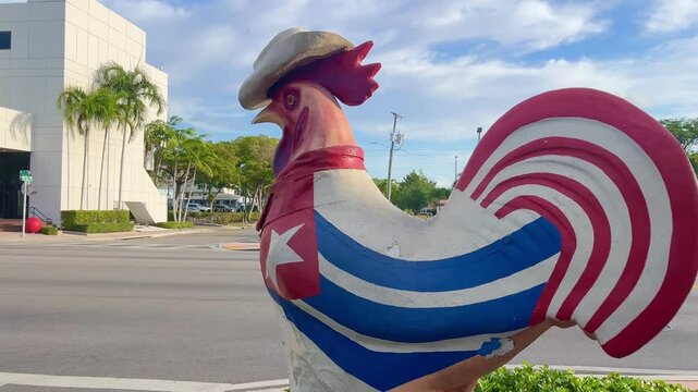 Vibrant rooster adorned with the Cuban flag and a cowboy hat, stands proudly on a street corner in Little Havana, Miami, symbolizing the neighborhood's rich cultural heritage