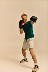 Handsome young man practicing boxing poses with enthusiasm indoors during a photoshoot
