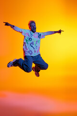 Young man joyfully leaps against a vibrant sunset backdrop celebrating freedom and happiness