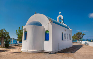 Christian orthodox church with white wall and blue dome on a square in Peloponnese Greece