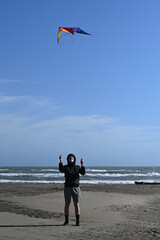 Teenage boy playing with a kite against blue sky