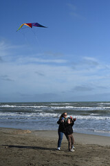 mother and child playing with a kite against a blue sky