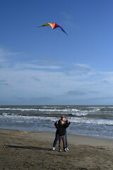 mother and child playing with a kite against a blue sky