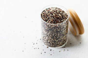 Mix of white, black and red quinoa seeds in glass jar.