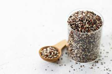 Mix of white, black and red quinoa seeds in wooden spoon.