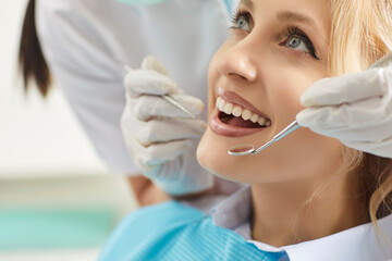Doctor dentist or nurse examining woman patient in clinic, using dental instrument for oral care, providing dentistry service and medicare in a professional atmosphere with attention.