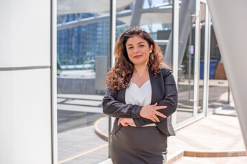 Fototapeta premium Cheerful Latin Woman with Curly Hair in Urban business&nbsp;style at city center