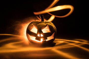 Halloween concept. Creepy silhouette in the dark corridor with pumpkin head. Toned light with fog on background.