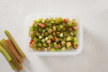 Freshly chopped green rhubarb prepared in box for frozen on white background. Trendy organic food....