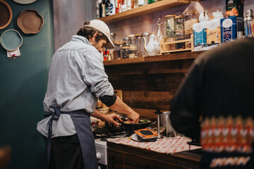 A person cooking in a small and inviting kitchen featuring wooden interior shelves lined with jars, utensils, and other cooking essentials. The atmosphere is warm and reflects a homely ambiance.