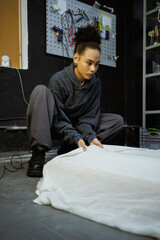African american craftswoman pulling carpet canvas in workshop