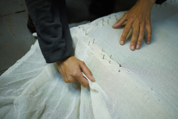 Partial shot of craftswoman fastening rug canvas on frame